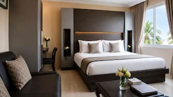 A hotel room with a bed, a sofa, a coffee table, and a view of palm trees.