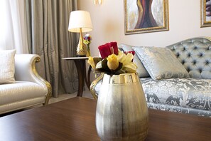 Una habitación con una mesa de madera, un sofá, una lámpara y un jarrón con flores.