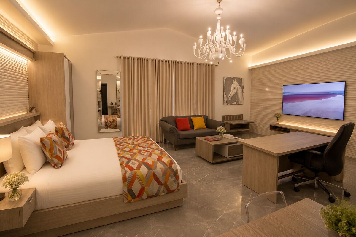 Una habitación de hotel moderna con cama, sofá, escritorio y televisión.