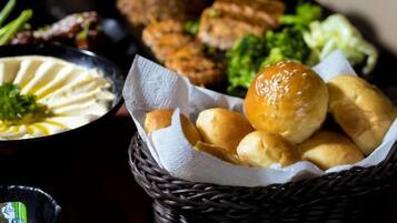 A basket of bread rolls on a table with various dishes in the background.