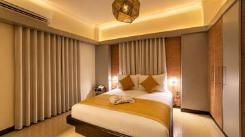 Une chambre d’hôtel avec un grand lit, des rideaux, un luminaire suspendu et une armoire.