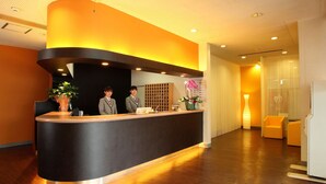 Un mostrador de recepción con dos empleados, suelo de madera y un diseño de interiores moderno.