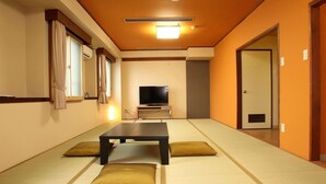 Una habitación con tatami, televisión, una mesa y cojines.