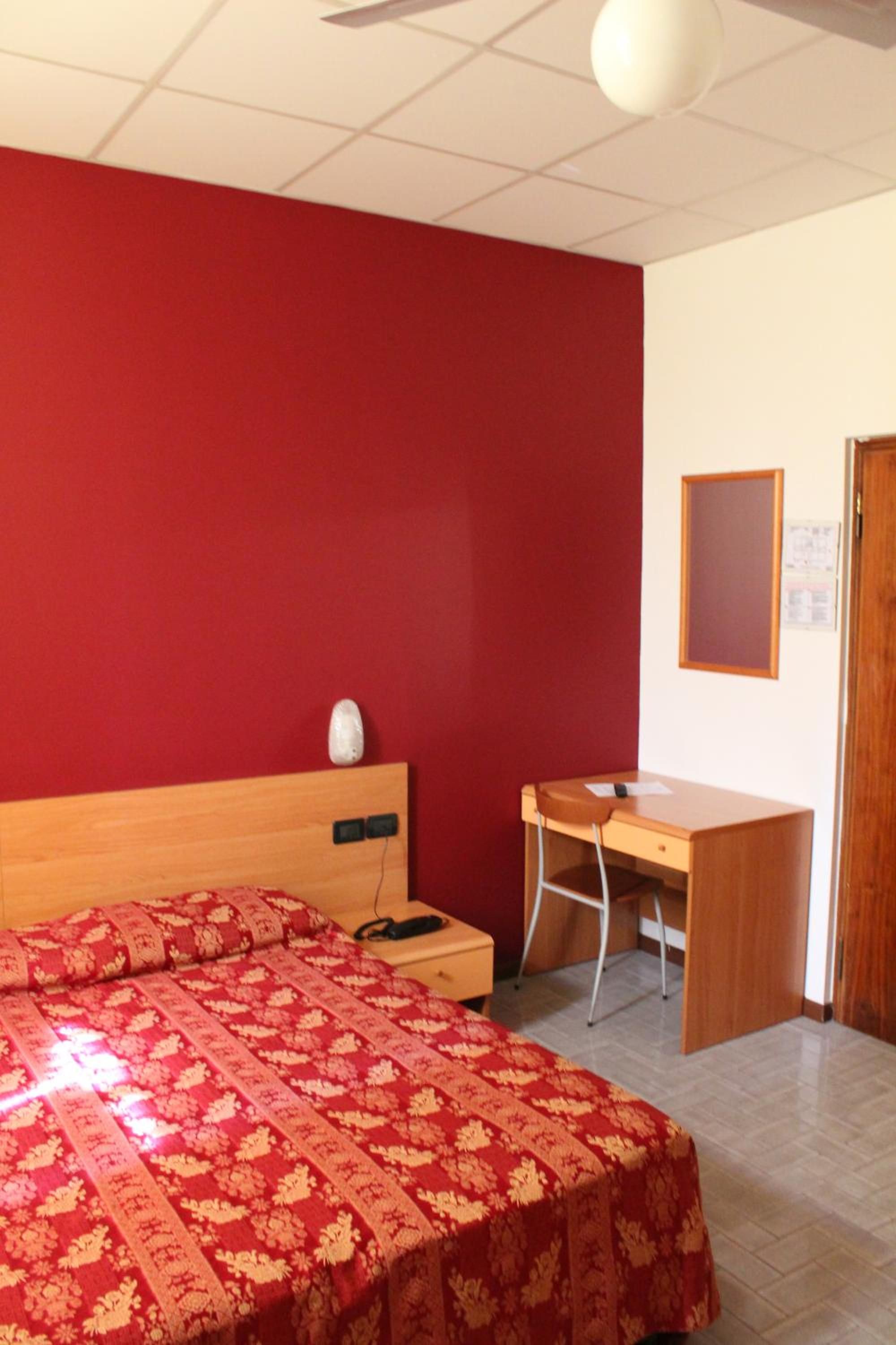 A bedroom with a bed, a desk, and a chair.