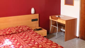 A bedroom with a bed, a desk, and a chair.