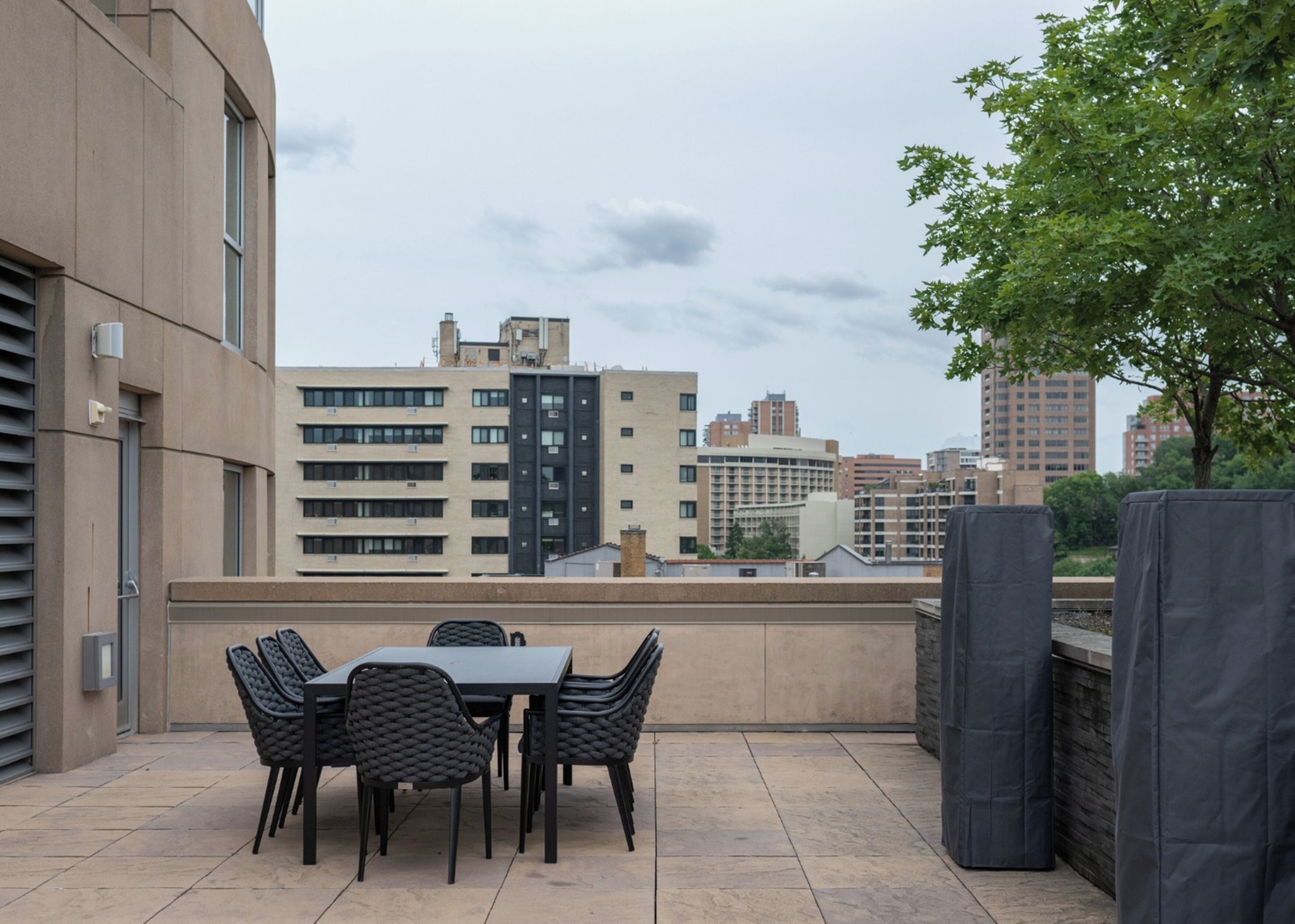 An outdoor patio with a table and chairs, a covered seating area, and a view of surrounding buildings.