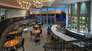 A hotel lobby with a curved staircase, seating areas, a bar, and a view of the night sky. - The Fontaine (Kansas City)