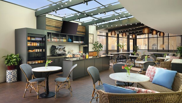 A modern outdoor dining area with wicker furniture, a bar, and a variety of food and drink options. - The Fontaine (Kansas City)
