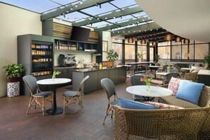 A modern outdoor dining area with wicker furniture, a bar, and a variety of food and drink options. - The Fontaine (Kansas City)