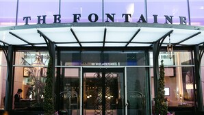 The entrance to The Fontaine hotel with a glass facade and a sign above the doors. - The Fontaine (Kansas City)
