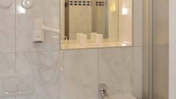 Un baño con lavamanos, espejo y ducha.