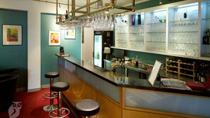 A bar area with stools, a wine cooler, and shelves with glasses and bottles.