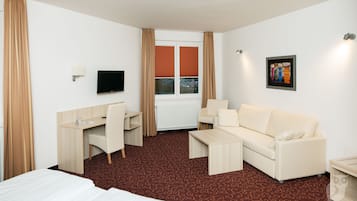 A hotel room with a bed, a desk, a sofa, and a TV.