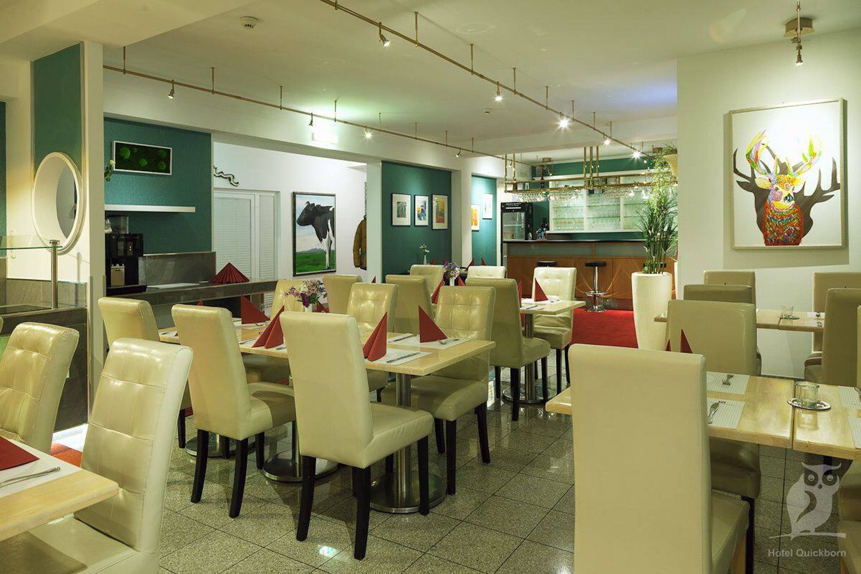 Un ristorante con diversi tavoli e sedie, un bancone e una parete decorata con quadri e uno specchio.