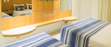 A hotel room with two beds, a TV mounted on the wall, and a wooden headboard.