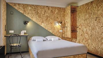 Una habitación con una cama, un escritorio y una silla. Hay un cartel en la pared y una lámpara sobre el escritorio.