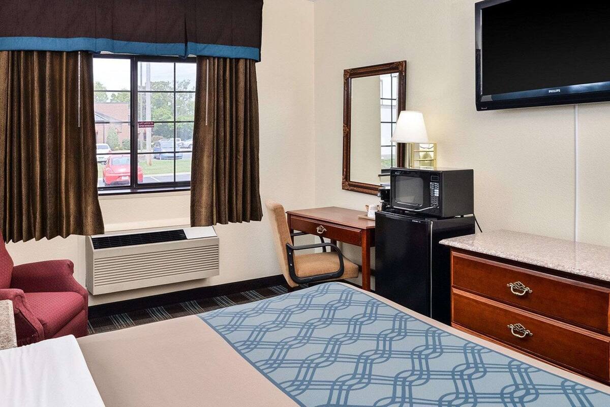 Une chambre d’hôtel équipée d’un lit, d’un bureau avec un ordinateur, d’une télévision et d’un four à micro-ondes.