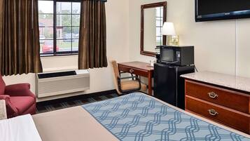 A hotel room with a bed, a desk with a computer, a television, and a microwave.