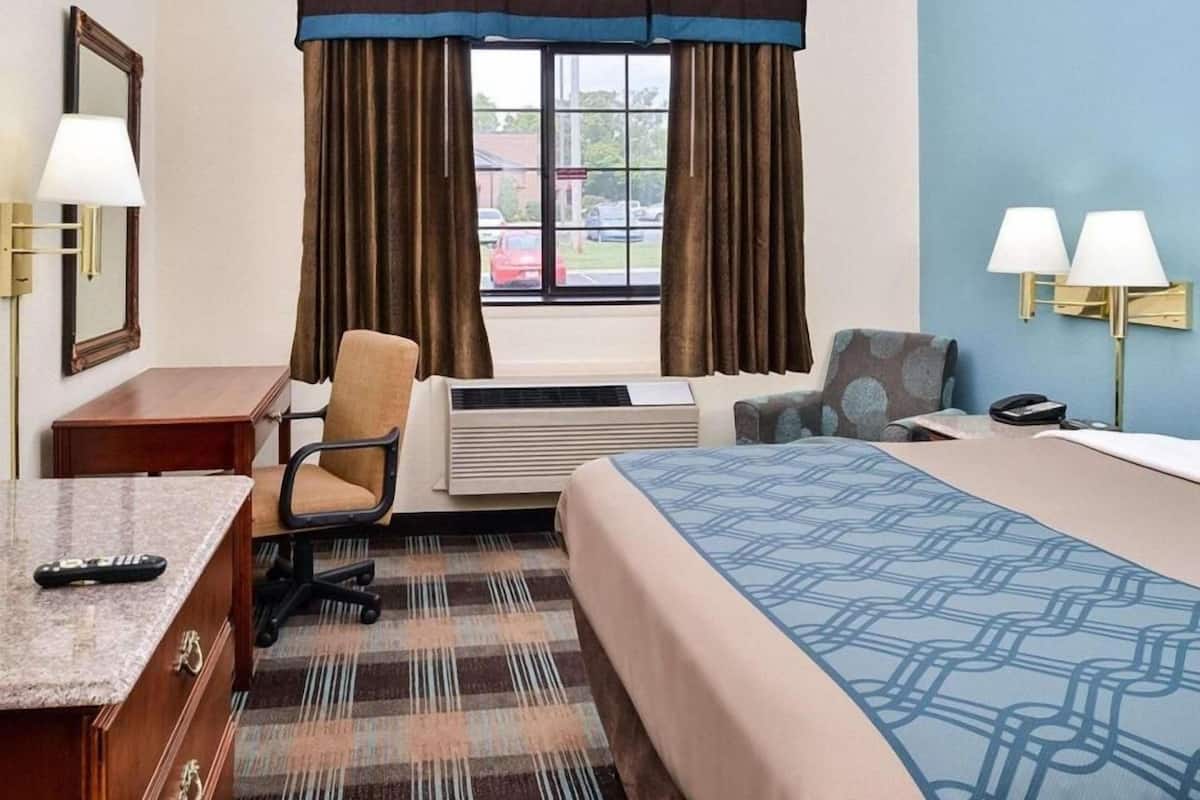 Une chambre d’hôtel équipée d’un lit, d’un bureau, d’une chaise, d’un appareil de climatisation et offrant une vue sur l’extérieur.