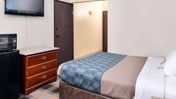 Una habitación de hotel con una cama, un aparador, un televisor montado en la pared y una puerta.