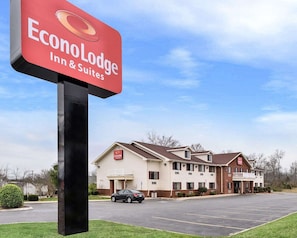 A sign for EconoLodge Inn & Suites with a parking lot and a building in the background.