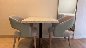 A dining table with two chairs, a marble top, and a round gold base. - Athens Hotel Suites (Houston)