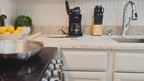 A kitchen with a stove, a bowl of lemons, a coffee maker, and a knife block. - Athens Hotel Suites (Houston)