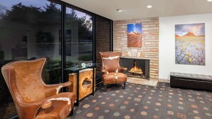 A modern living room with leather armchairs, a glass coffee table, a fireplace, and artwork on the walls. - Best Western Red Hills (Kanab)