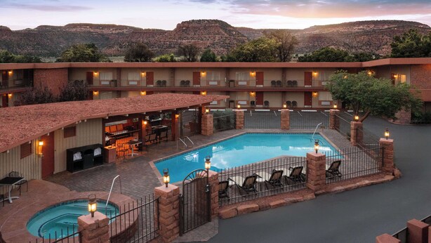 A hotel with a pool, outdoor seating, and a mountainous backdrop. - Best Western Red Hills (Kanab)