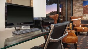 A modern office space with a glass desk, two monitors, a keyboard, and leather chairs. - Best Western Red Hills (Kanab)