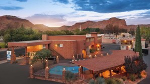 A hotel with a pool, outdoor seating, and a mountainous backdrop. - Best Western Red Hills (Kanab)
