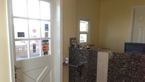 A reception area with a door, a counter, and a window with a view of the street. - BeachWay Inn (Arroyo Grande)