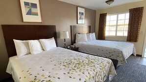 A hotel room with two beds, a nightstand, a lamp, and two framed pictures on the wall. - BeachWay Inn (Arroyo Grande)