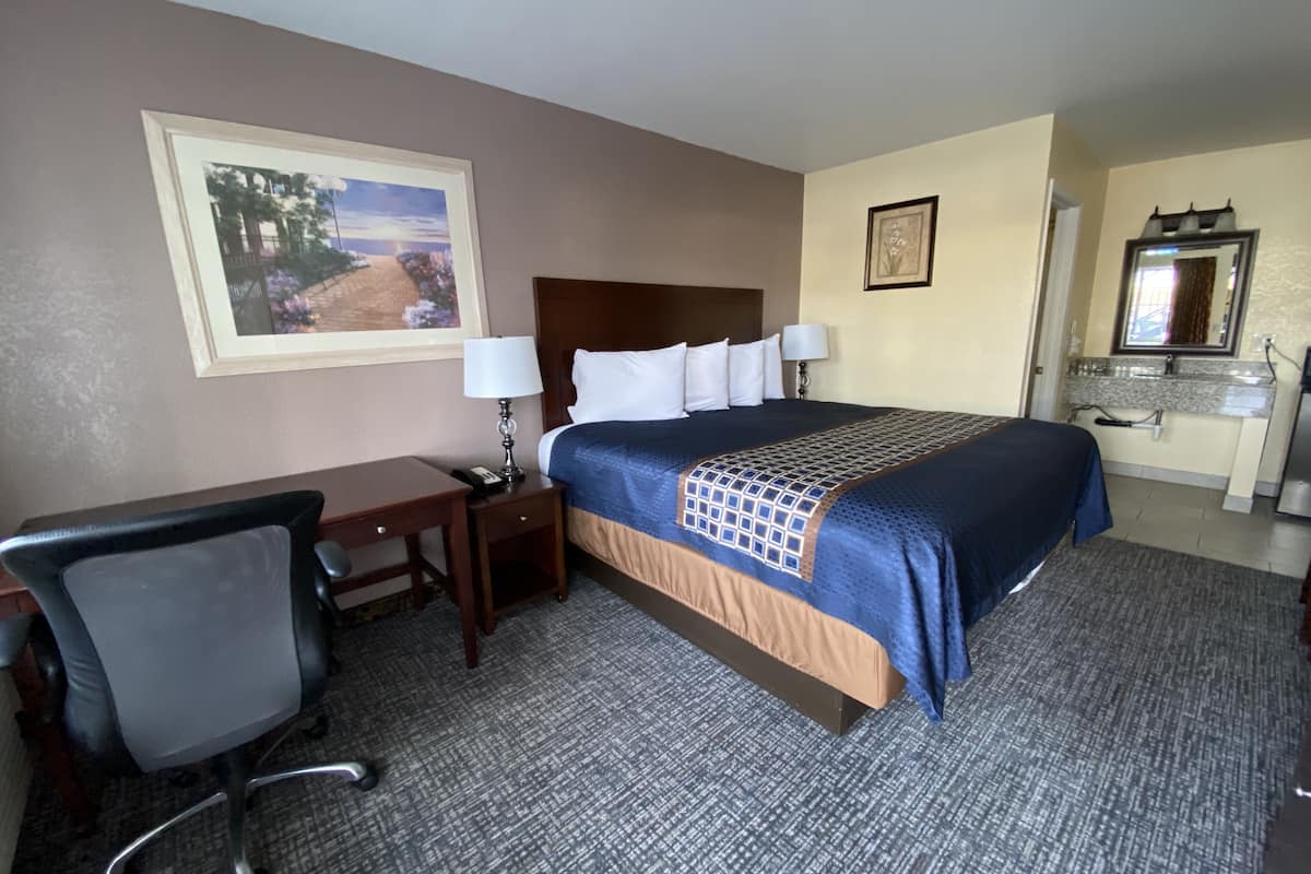 A hotel room with a bed, desk, chair, and a bathroom.