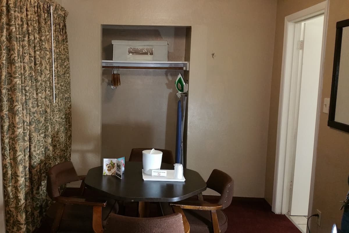 A dining area with a round table, four chairs, a non-smoking sign, a white cabinet, and a door.