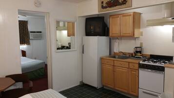 A compact kitchen with a refrigerator, stove, and wooden cabinets.