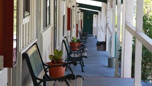 A covered porch with benches and potted plants. - El Dorado Motel (Twain Harte)