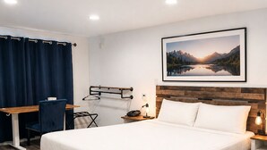 A hotel room with a bed, desk, chair, and a wall-mounted coat rack. - El Dorado Motel (Twain Harte)