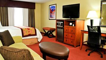 Una habitación de hotel con una cama, un escritorio, un televisor, un microondas y una silla.