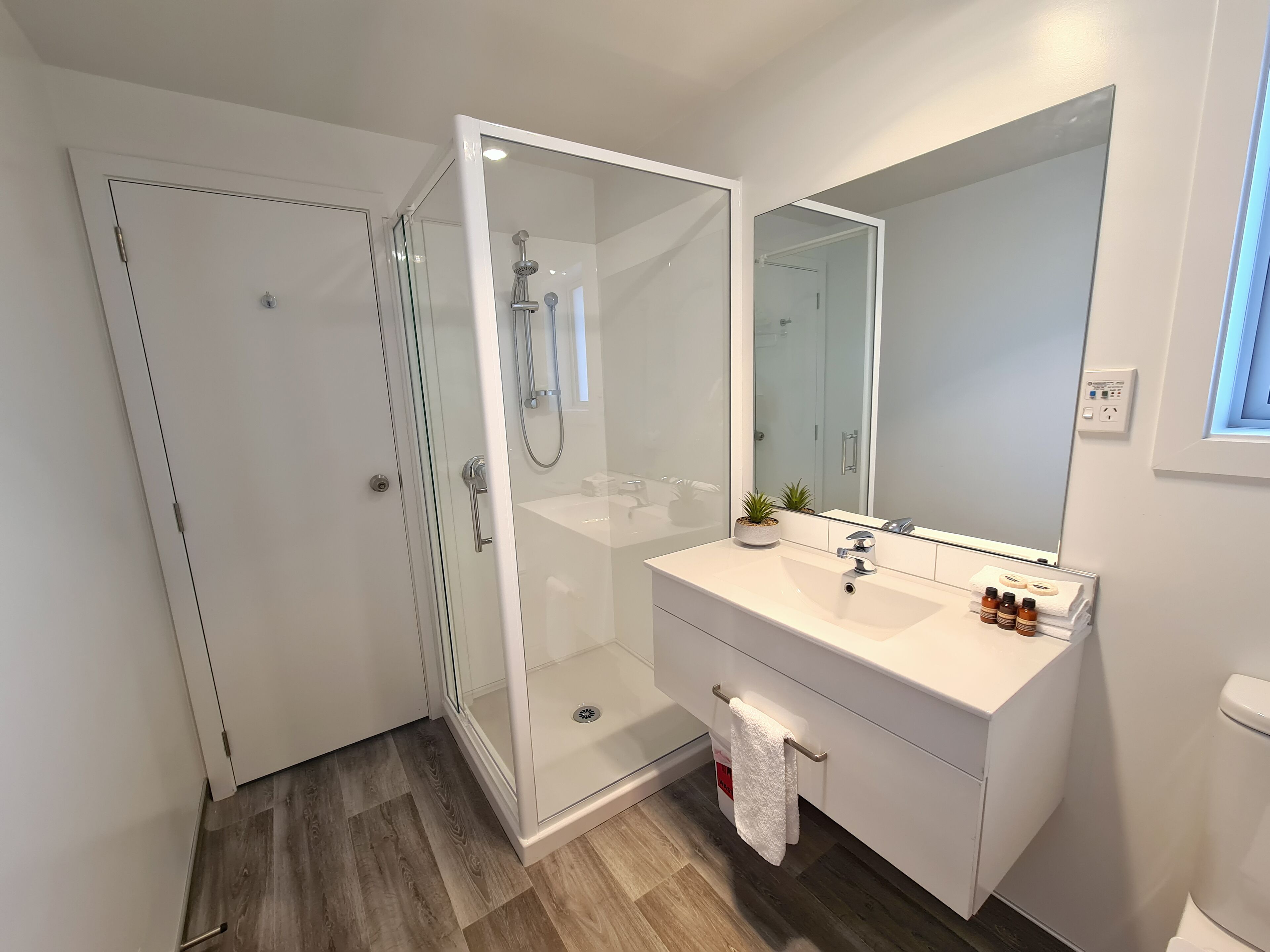 A modern bathroom with a glass-enclosed shower, a white vanity with a mirror, and a towel rack.