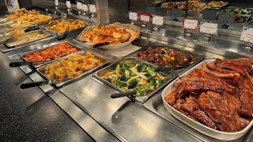 Un buffet proposant divers plats, notamment du poulet frit, des crevettes, des légumes sautés et du bœuf braisé.