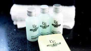 Tres botellas de champú y acondicionador L'S Lone Star, una pastilla de jabón blanca y una toalla negra con la inscripción 'Makeup Remover'.