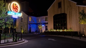 A building with a neon sign reading "Lone Star" and a parking lot in front. - Lone Star Court, by Valencia Hotel Collection (Austin)