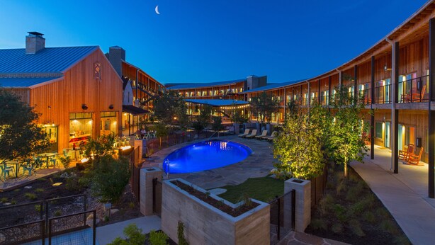 A courtyard with a swimming pool, wooden buildings, and outdoor seating areas. - Lone Star Court, by Valencia Hotel Collection (Austin)