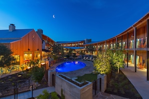 A courtyard with a swimming pool, wooden buildings, and outdoor seating areas.