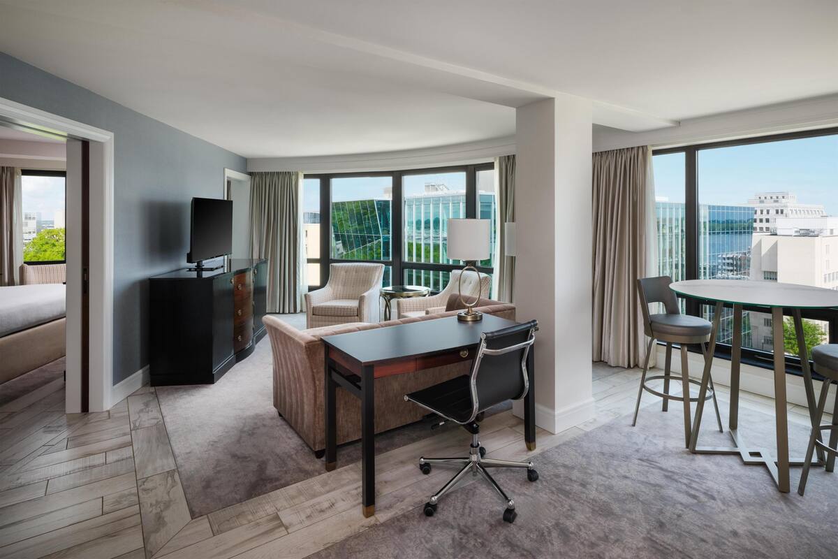 Une chambre d’hôtel moderne dotée d’une grande fenêtre, d’un bureau, d’un canapé et d’un coin repas.