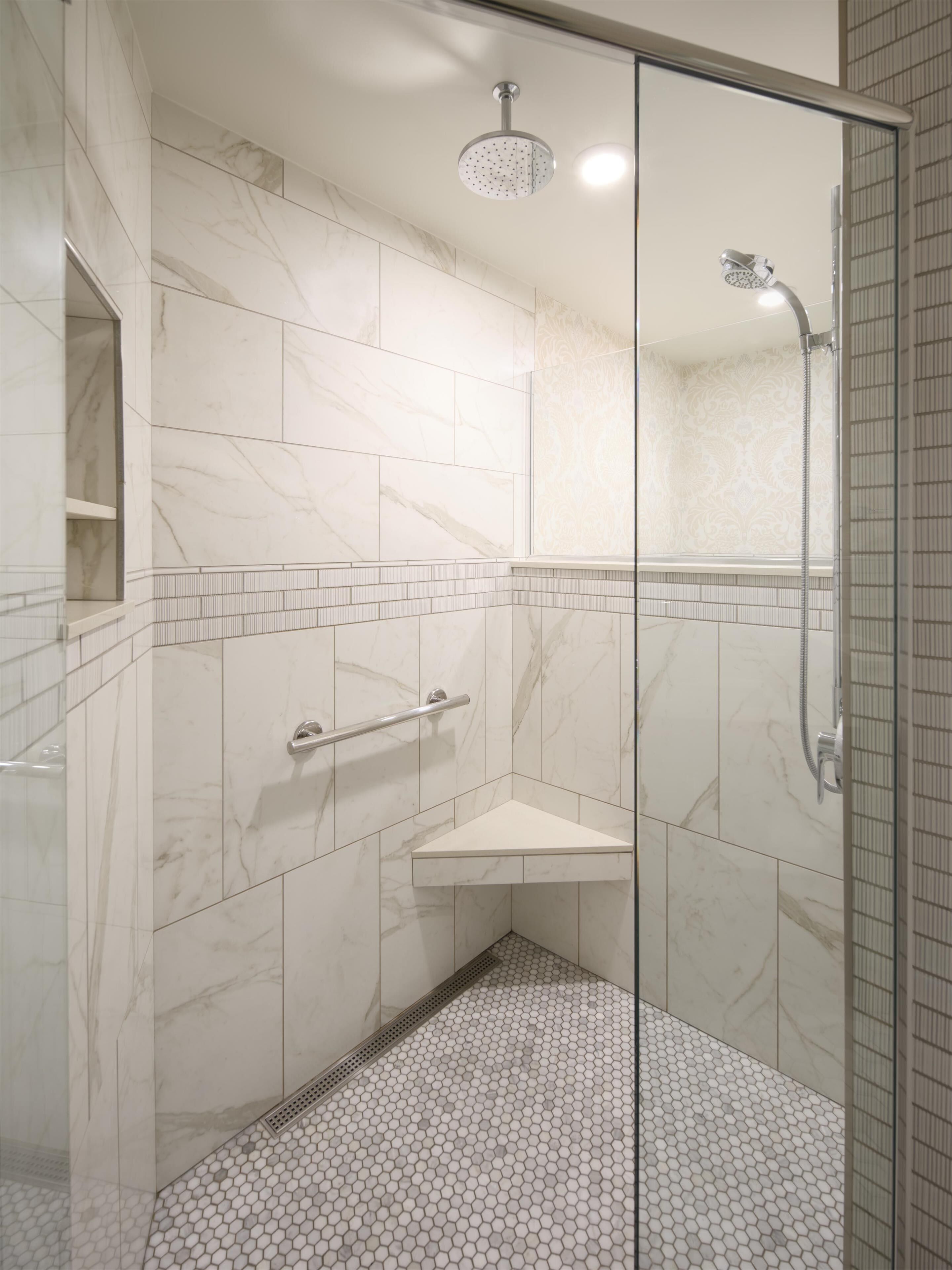 A shower with a glass door, a handheld showerhead, and a wall-mounted faucet.