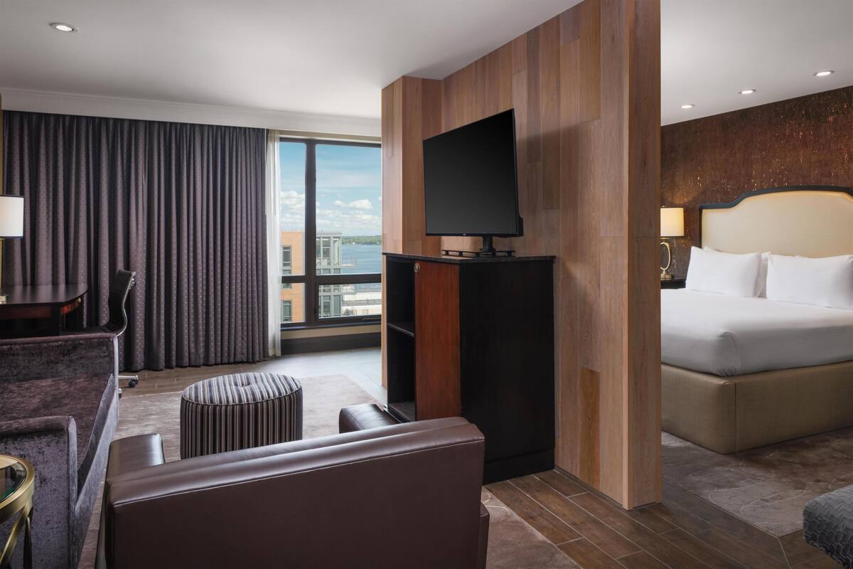 Une chambre d’hôtel équipée d’un lit, d’une télévision, d’un coin salon et offrant une vue sur la ville.