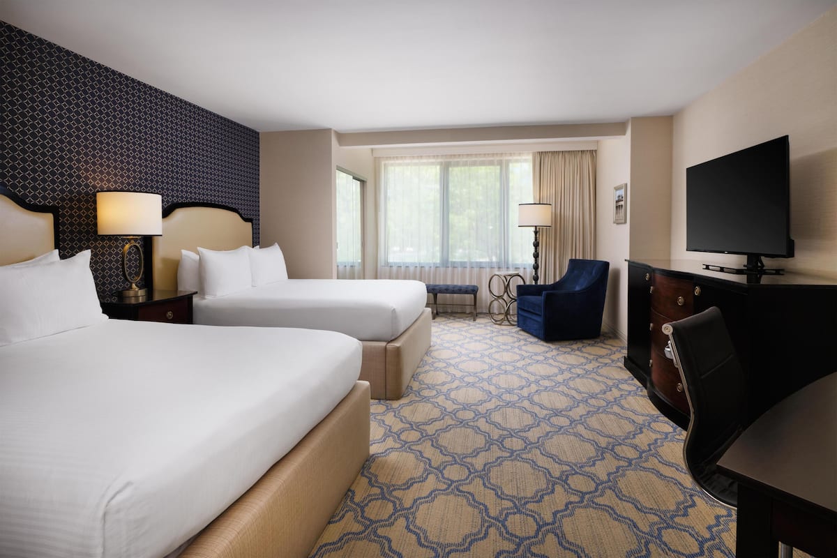 Une chambre d’hôtel avec deux lits, une télévision, un bureau et une chaise.