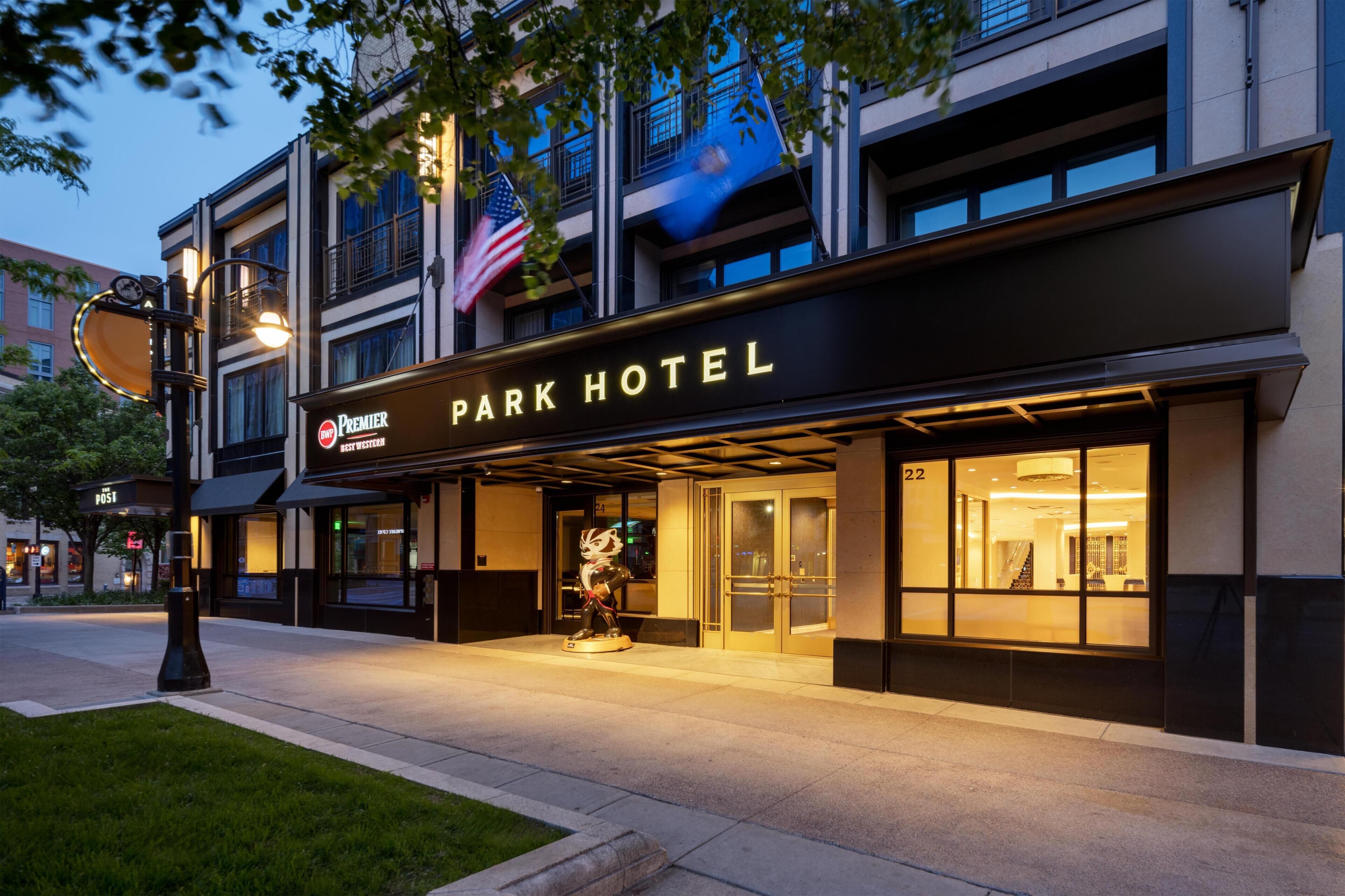 Ein Hotel mit einer markanten Eingangsfassade, einer Beschilderung mit dem Schriftzug 'Park Hotel' und einer amerikanischen Flagge.